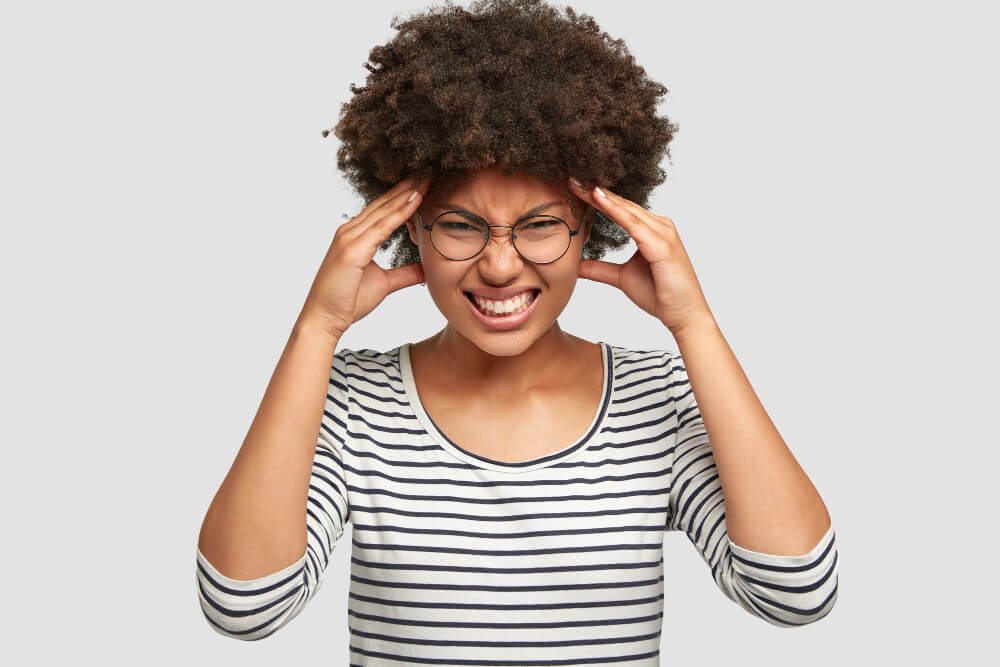 mulher com as mãos na cabeça representando o estresse crônico