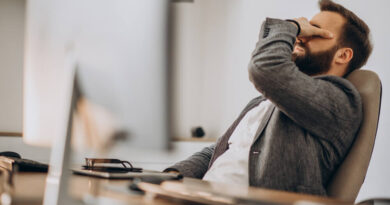 O que acontece com seu corpo se você viver sempre no limite homem sentado na cadeira em frente ao computador e com expressão de estresse representando viver no limite do corpo