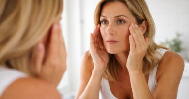 Hábitos que aceleram o envelhecimento da pele e da mente depois dos 40 Mulher loira observando sinais de envelhecimento no espelho