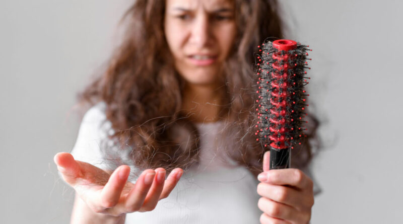 Mulher preocupada com cabelo caindo muito ao segurar fios e escova com queda de cabelo
