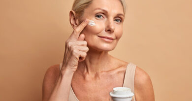 Cuidados com a pele: 4 erros que podem estar prejudicando sua rotina Mulher madura aplicando creme no rosto durante rotina de cuidados com a pele em fundo neutro