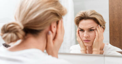 “Cortisol face”: a trend do TikTok sobre rosto inchado tem fundamento? Mulher observa o rosto no espelho com expressão de preocupação, em referência à trend “cortisol face” e ao inchaço facial.