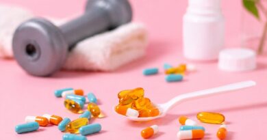 Suplementos alimentares em cápsulas e gel ao lado de halter, representando uso de suplementos para treino e saúde