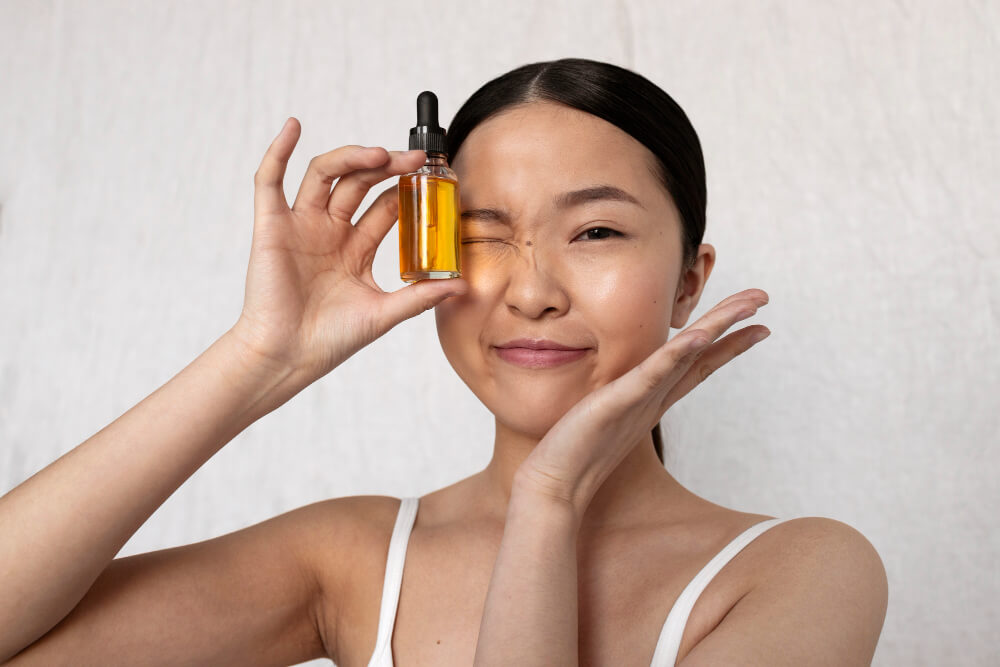 Mulher segurando frasco de skincare próximo ao rosto em rotina de cuidados com a pele