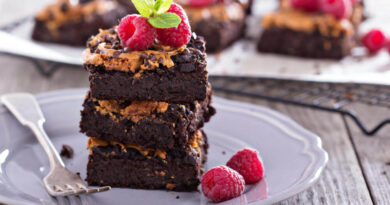 3 sobremesas saudáveis com cara de confeitaria (e sem açúcar) Brownie de chocolate com framboesas, hortelã e cobertura cremosa, servido em prato cinza sobre mesa de madeira