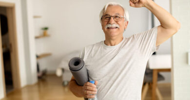 Healthspan: por que viver mais não é o mesmo que viver bem Homem idoso sorridente com o punho erguido, segurando tapete de exercício e garrafa de água, símbolo de vitalidade e healthspan
