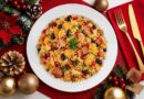 Farofa de Natal com bacon, linguiça, frutas secas e ervas, servida em prato branco sobre mesa decorada com elementos natalinos.