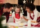 Família cozinhando junta em cozinha decorada para a ceia de Natal, com uma menina misturando farinha em uma tigela