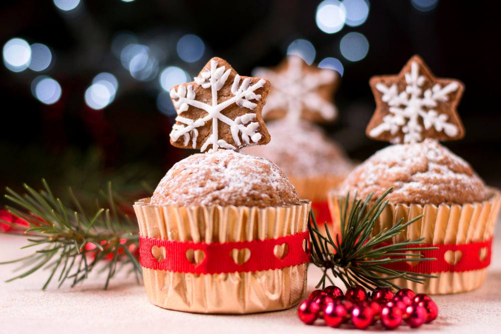 Cupcakes natalinos decorados com biscoitos em formato de estrela, açúcar de confeiteiro e enfeites de Natal.